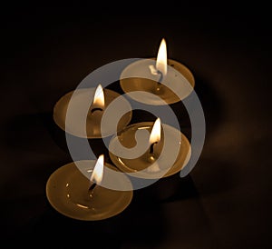 Group of burning small candles on a black background.