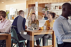 Group Of Business Colleagues Having Informal Meeting Around Table In Office Coffee Shop