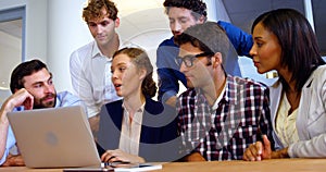 Group of business executives discussing over laptop