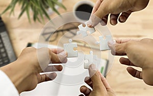 Group of business with hands together connecting piece of jigsaws puzzle at office