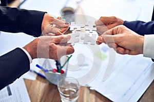 Group of business hands trying to connect puzzle pieces at office