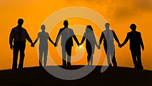 Group of business partner hold hand together in silhouette with sunrise background