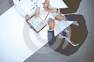 Group of business people analyzing financial documents, view from above. Business team at meeting