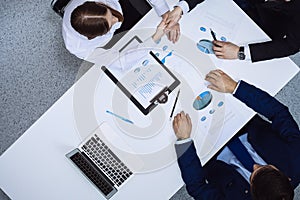 Group of business people analyzing financial documents, view from above. Business team at meeting