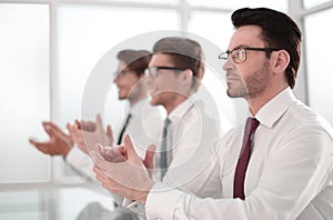 Group of business people applauding sitting at the office table.