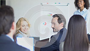 Group Of Business People Asking Question To Businesswoman Leading Presentation In Modern Conference Hall