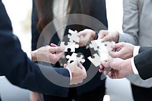 Group of business people assembling jigsaw puzzle, team support