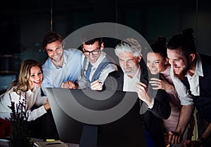 A group of business people with computer in an office, expressing excitement.