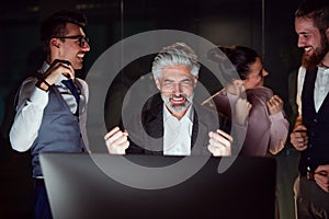 A group of business people with computer in an office, expressing excitement.
