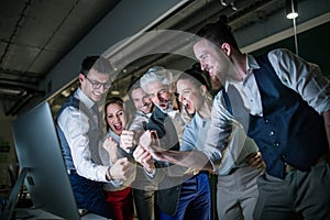 A group of business people with computer in an office, expressing excitement.
