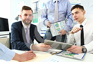 Group of business people discussing charts on paper and digital tablet