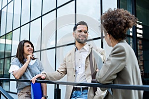 Group of business people discussing ideas at meeting outside. Businesswoman and businessman outdoor near office building talking
