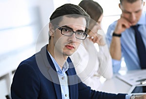 Group of business people discussing questions at meeting in modern office. Headshot of businessman at negotiation