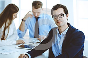 Group of business people discussing questions at meeting in modern office. Headshot of businessman at negotiation