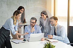 Group of business people engaging in a productive office meeting, using laptop while working together on a project.