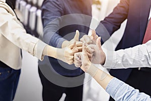 Group of Business people giving thumbs up gesture of approval an success, huddle together, showing unity and teamwork at office