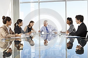 Group Of Business People Having Board Meeting Around Glass Table