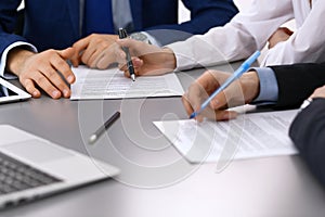 Group of business people and lawyer discussing contract papers sitting at the table, closeup. Businessman is signing