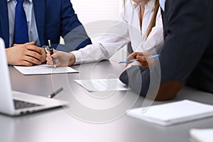 Group of business people and lawyer discussing contract papers sitting at the table, closeup. Businessman is signing