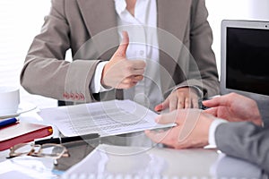 Group of business people or lawyers at meeting discussing contract papers. Woman showing thumb up