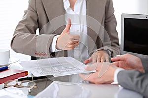 Group of business people or lawyers at meeting discussing contract papers. Woman showing thumb up