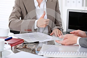 Group of business people or lawyers at meeting discussing contract papers. Woman showing thumb up