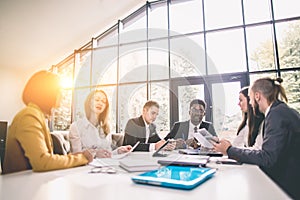 Group Of Business People Listening To Colleague Addressing Office Meeting