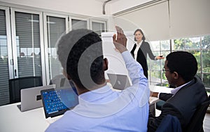 Group Of Business People Listening To Colleague Addressing Office Meeting