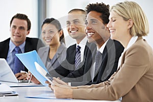 Group Of Business People Listening To Colleague Addressing Office Meeting