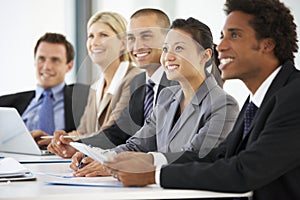 Group Of Business People Listening To Colleague Addressing Office Meeting