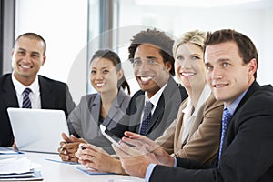 Group Of Business People Listening To Colleague Addressing Office Meeting