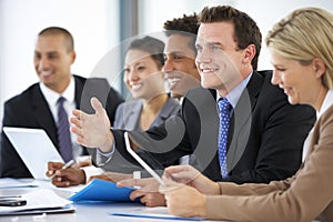 Group Of Business People Listening To Colleague Addressing Office Meeting