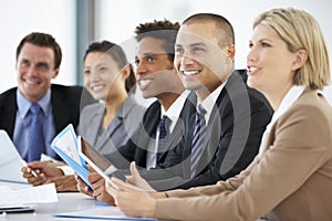 Group Of Business People Listening To Colleague Addressing Office Meeting