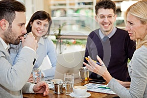 Group of business people meeting in coffee shop and holding a b