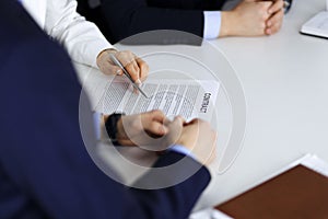 Group of business people, men and a woman, discuss details of a contract at meeting in a modern office. Discussion at