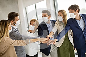 Group of business people with protective facial masks holding hands together