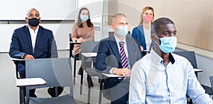 Group of business people in protective masks listening to presentation