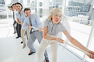 Group of business people pulling rope in office