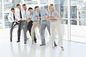 Group of business people pulling rope in office