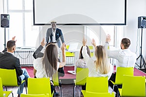 Group of business people raise hands up to agree with speaker in the meeting room seminar. Business meeting