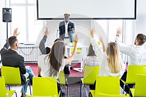 Group of business people raise hands up to agree with speaker in the meeting room seminar. Business meeting