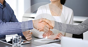 Group of business people shaking hands after discussing questions at meeting in modern office. Handshake close-up