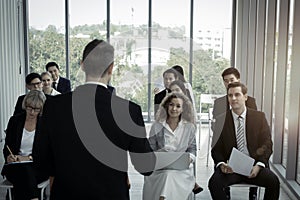 Group of business people sitting on conference together listening to the speaker giving a speech in the meeting room seminar  The