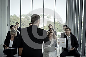 Group of business people sitting on conference together listening to the speaker giving a speech in the meeting room seminar The