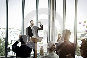 Group of business people sitting on conference together listening to the speaker giving a speech in the meeting room seminar