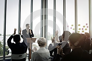 Group of business people sitting on conference together listening to the speaker giving a speech in the meeting room seminar