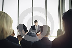 Group of business people sitting on conference together listening to the speaker giving a speech in the meeting room seminar