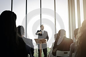 Group of business people sitting on conference together listening to the speaker giving a speech in the meeting room seminar