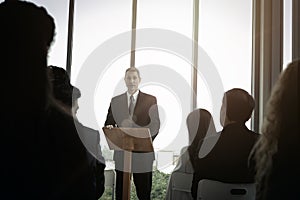 Group of business people sitting on conference together listening to the speaker giving a speech in the meeting room seminar