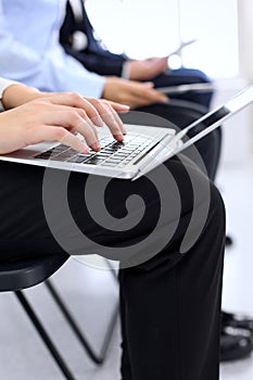Group of business people sitting in office waiting for job interview, close-up. Hands of woman working on laptop